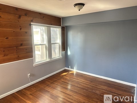 A room with wooden floors and a window with blinds.
