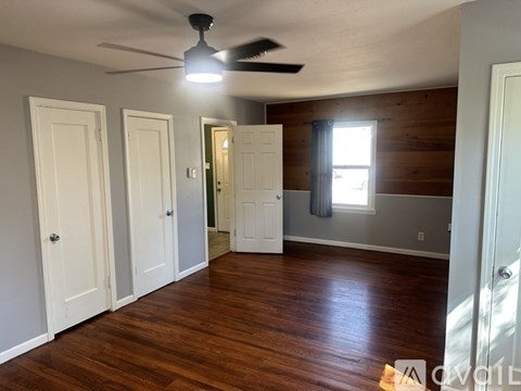 A room with a ceiling fan and wooden floors.