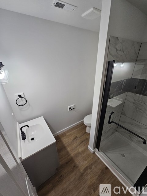 A bathroom with a toilet, sink, and shower.