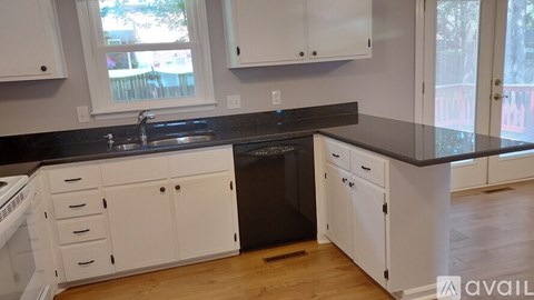 A kitchen with white cabinets and a black dishwasher.