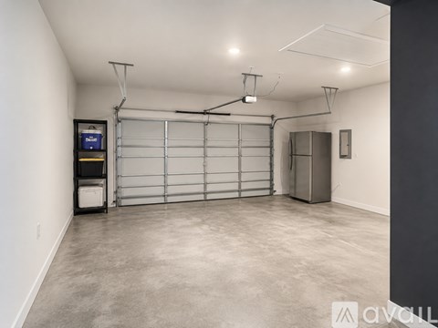A spacious garage with a closed white door and a black trash bin.