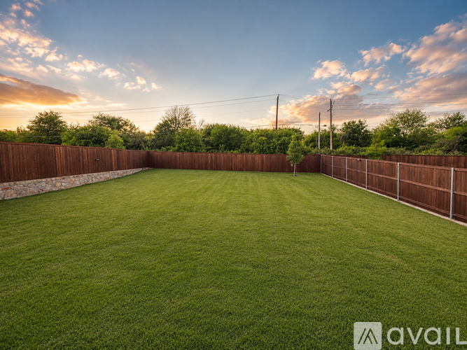 A backyard with a wooden fence and green grass.
