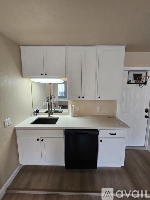 A kitchen with white cabinets and a black dishwasher.
