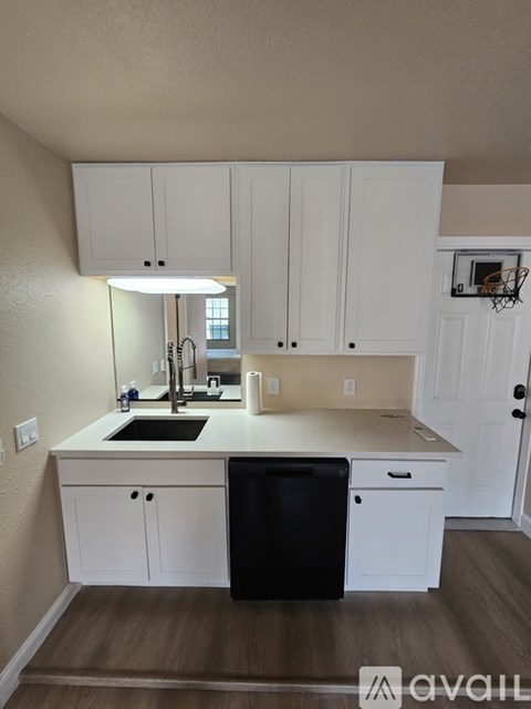 A kitchen with white cabinets and a black dishwasher.