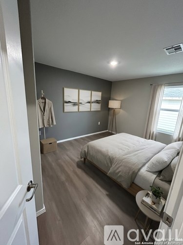 A bedroom with a bed, nightstand, and a window with blinds.