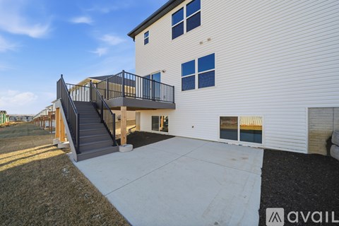 A modern house with a white exterior and a balcony with a black railing.