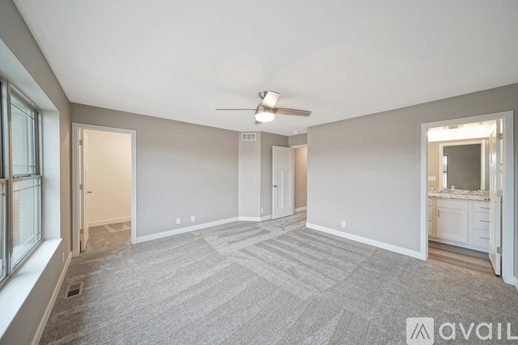A spacious room with a carpeted floor and a ceiling fan.