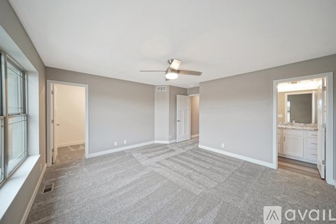 A spacious room with a carpeted floor and a ceiling fan.