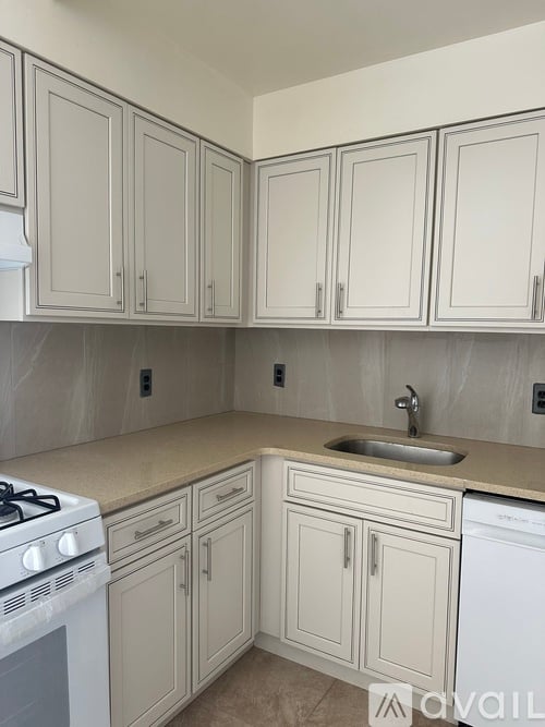 A kitchen with white cabinets and a stove top oven.