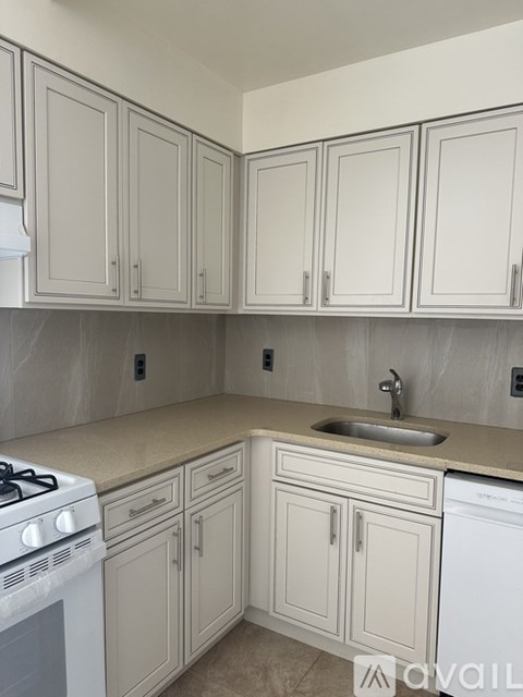 A kitchen with white cabinets and a stove top oven.
