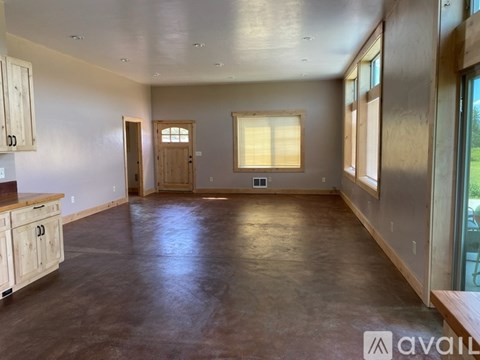 A spacious room with wooden floors and a window with blinds.