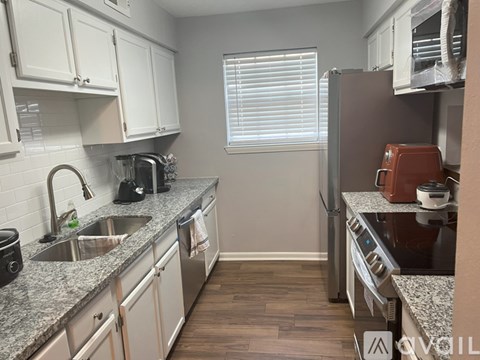 A kitchen with a sink, stove, and cabinets.