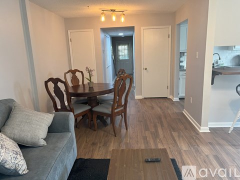 A living room with a grey couch and a wooden dining table with chairs.