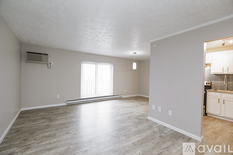 A spacious living room with a large window and hardwood flooring.