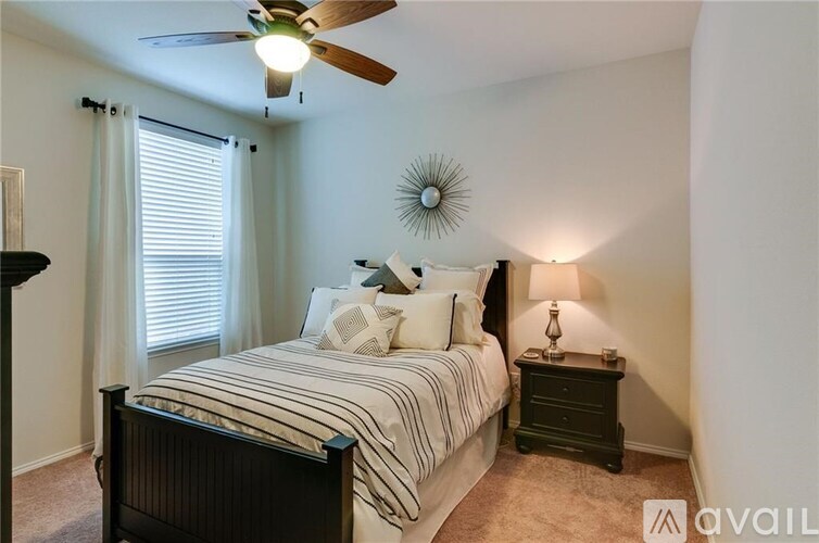 A bedroom with a bed, nightstand, and window with blinds.