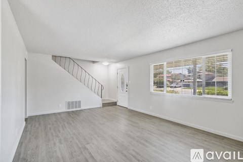 A spacious room with a staircase and a window showing an outdoor view.