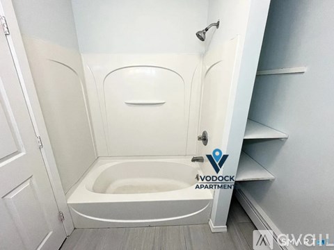 A white bathtub in a small bathroom with a shower head.