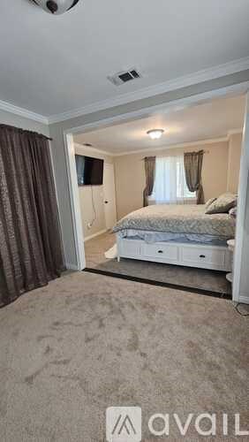 A bedroom with a bed, a television, and a carpeted floor.
