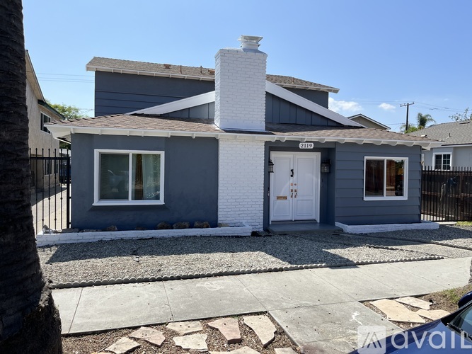 A house with a grey exterior and a white door is for sale.