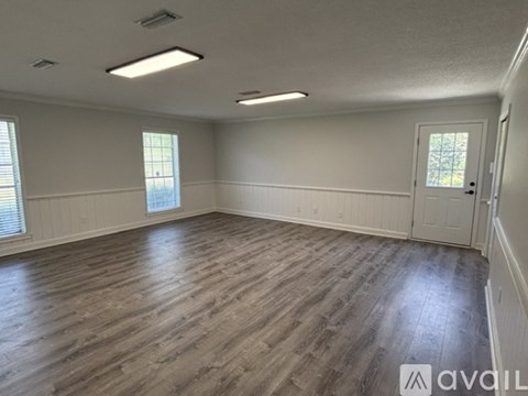 A spacious room with wooden flooring and white walls.