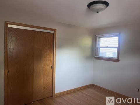 A room with a wooden door and a window with blinds.