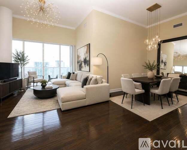 A modern living room with a white sofa set, a black coffee table, and a chandelier.