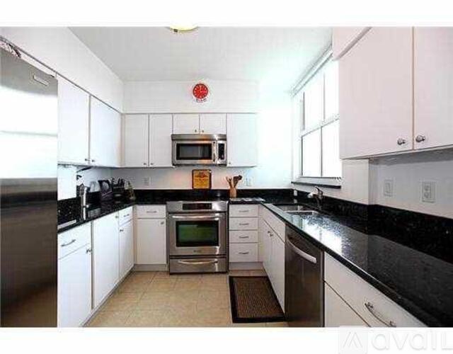 A kitchen with white cabinets and black countertops.
