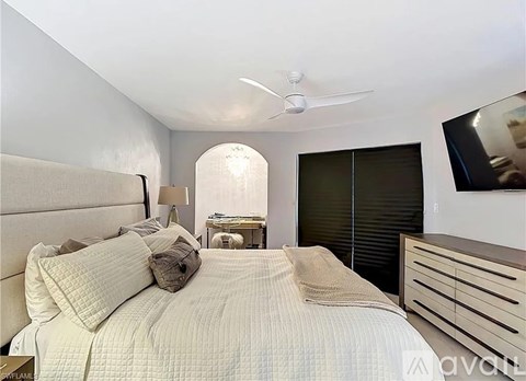 A bedroom with a large bed and a ceiling fan.