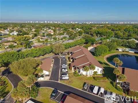A bird's eye view of a residential area with houses, cars, and a swimming pool.