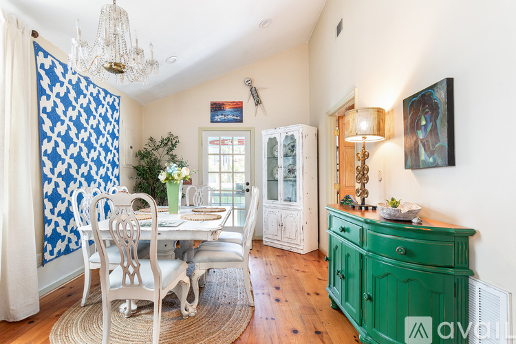 A dining room with a table set for two and a chandelier hanging from the ceiling.