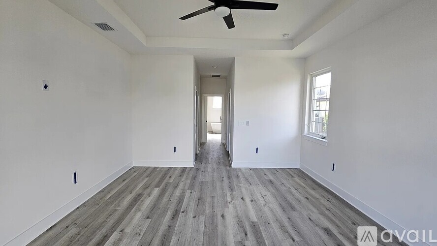 A spacious room with a ceiling fan and wooden flooring.