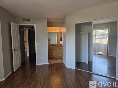 A spacious room with wooden floors and a large mirror on the wall.