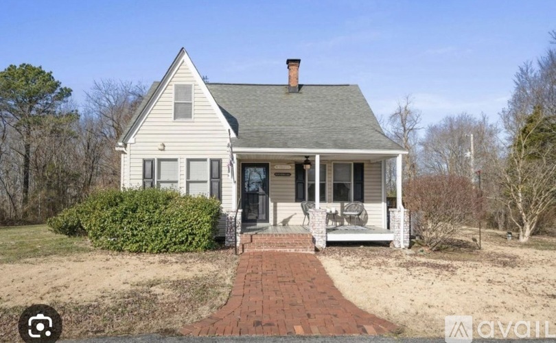 A white house with a brick pathway leading to the front door.