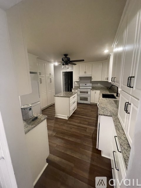 A kitchen with white cabinets and a ceiling fan.