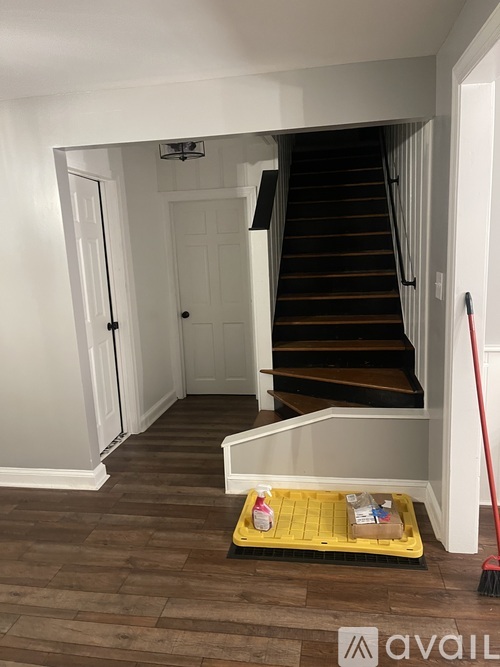 A broom is leaning against a wall next to a staircase.