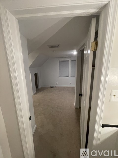 A hallway with a carpeted floor and white walls.