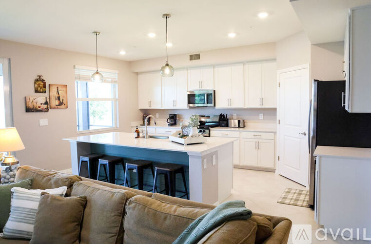 A kitchen with white cabinets and a large island with a bar stool.