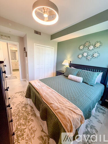 A bedroom with a bed and a lamp on the wall.