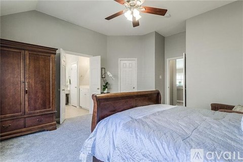 A bedroom with a large bed and a wooden armoire.