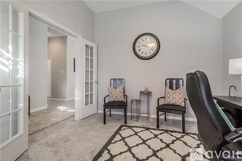 A living room with a black chair and a clock on the wall.