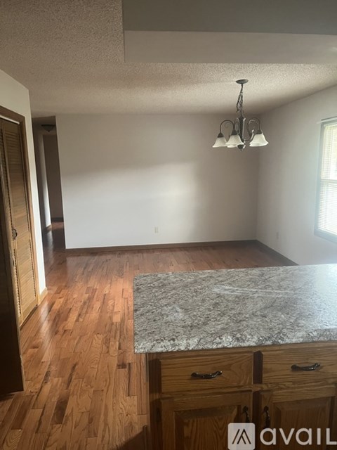 A kitchen with a granite countertop and wooden cabinets.
