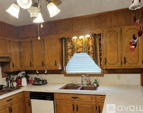 A kitchen with wooden cabinets and a window with blinds.