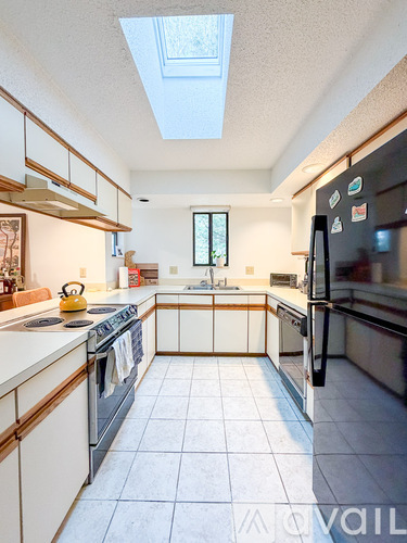 A kitchen with a black fridge and white cabinets.