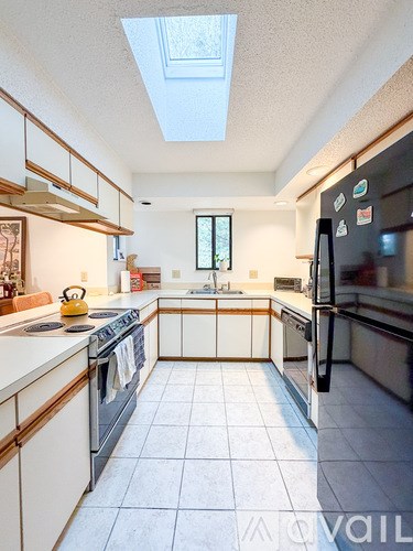 A kitchen with a black fridge and white cabinets.
