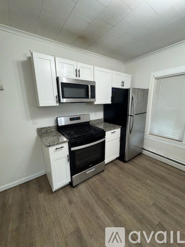 A kitchen with white cabinets and a black fridge.