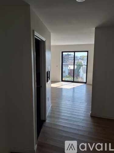 A hallway with wooden floors and a glass door leading to a balcony.