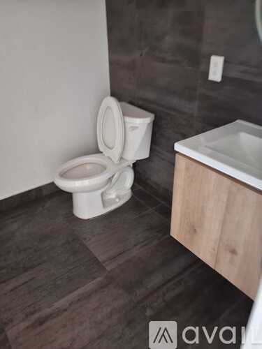 A white toilet is in a bathroom with a wooden vanity.