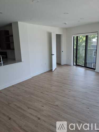 A spacious room with wooden flooring and white walls.