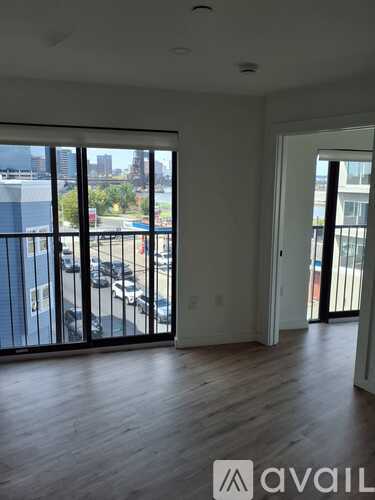 A room with a view of a parking lot and buildings outside.
