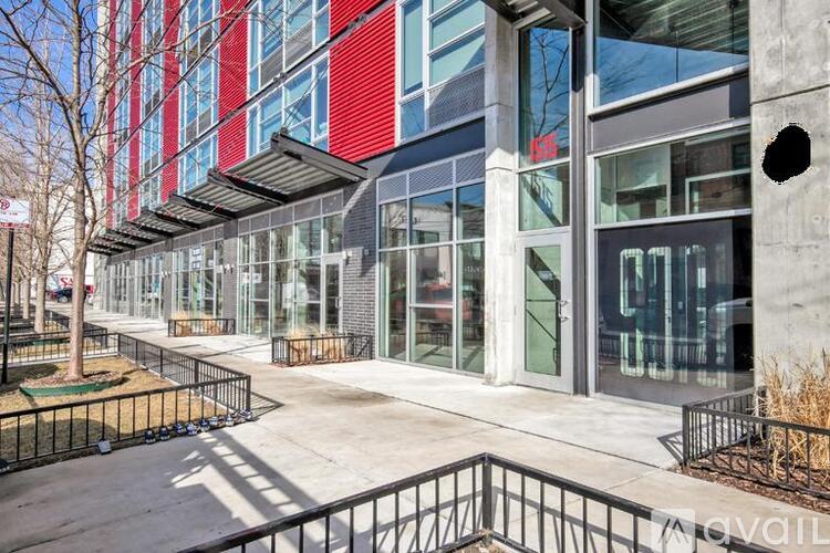 A modern building with a red and blue facade and a black fence in front.